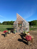 Wooden greenhouse with plants and flowers in a rural setting