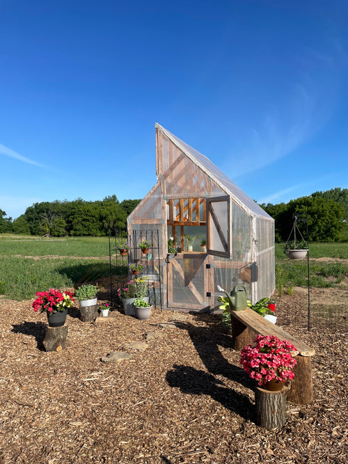 Wooden greenhouse with plants and flowers in a rural setting